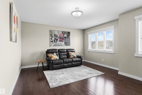 Spacious interior with dark wood-finish flooring, light-toned walls, and abundant natural light from multiple windows - 8515 19 Avenue Sw, Edmonton, AB 