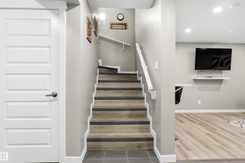 Staircase with wood-finish treads and white risers, grey wall paint, and recessed lighting - 8515 19 Avenue Sw, Edmonton, AB 