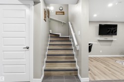 Staircase with wood-finish treads and white risers, grey wall paint, and recessed lighting - 