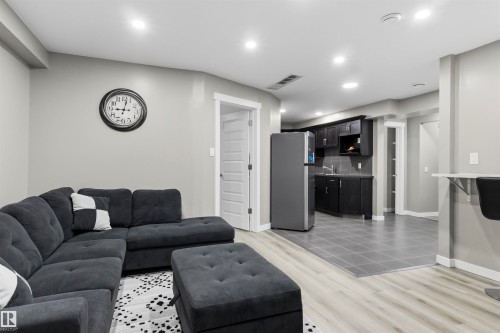 Recessed lighting throughout, wood-finish flooring, dark wood-finish cabinetry, stainless steel refrigerator, and a built-in wall bar - 8515 19 Avenue Sw, Edmonton, AB 