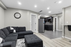 Recessed lighting throughout, wood-finish flooring, dark wood-finish cabinetry, stainless steel refrigerator, and a built-in wall bar - 