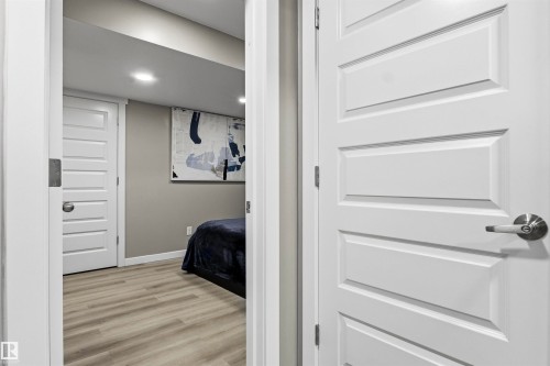 Recessed lighting, wood-finish flooring, and a paneled door with contemporary hardware - 8515 19 Avenue Sw, Edmonton, AB 