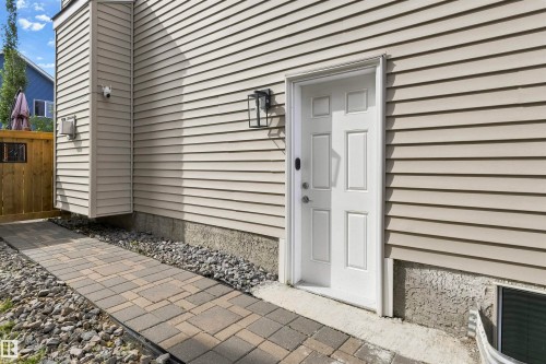 Cream-colored horizontal siding with a white paneled door and black exterior light fixture - 8515 19 Avenue Sw, Edmonton, AB 