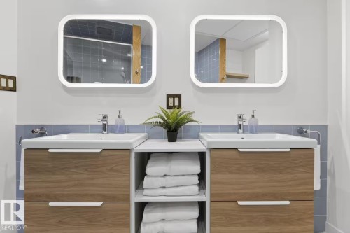 Double vanity featuring wood-finish cabinetry and white integrated sinks - #501 10105 109 St Nw, Edmonton, AB 