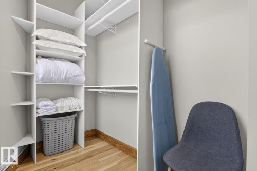 Custom closet system featuring white shelving and hanging rods over wood-finish flooring - #501 10105 109 St Nw, Edmonton, AB 