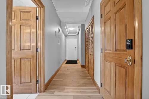 Wood-finish flooring throughout, complemented by light wood panel doors with brass hardware - #501 10105 109 St Nw, Edmonton, AB 