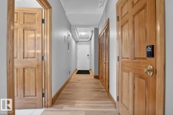 Wood-finish flooring throughout, complemented by light wood panel doors with brass hardware - 