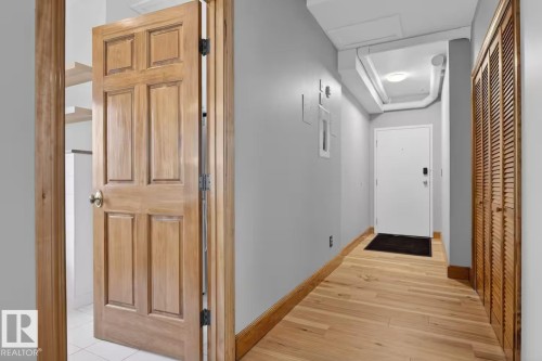 Wood-finish flooring, light gray wall paint, wood louvered doors, and a paneled wood door - #501 10105 109 St Nw, Edmonton, AB 