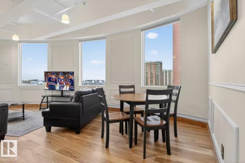 Hardwood flooring throughout, multiple large windows, decorative wall panels, and pendant lighting - #501 10105 109 St Nw, Edmonton, AB 