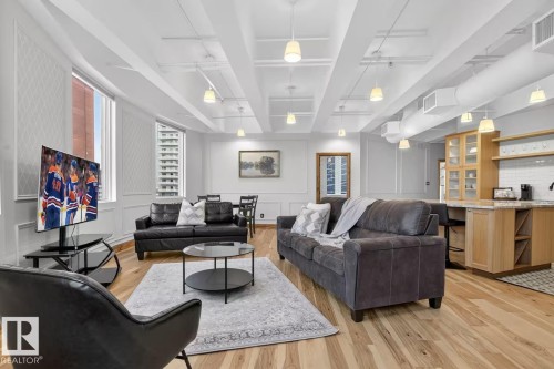 Hardwood-finish flooring, exposed ceiling beams, recessed and pendant lighting, wainscoting, and a built-in wet bar with cabinetry - #501 10105 109 St Nw, Edmonton, AB 