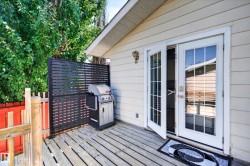 Wooden deck with horizontal privacy screen, white French doors with glass panes, and beige siding - 