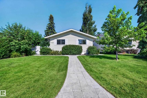 Single-story residence featuring light-colored siding, a pitched roof, and a paved walkway - 7704 13 Avenue Nw, Edmonton, AB 