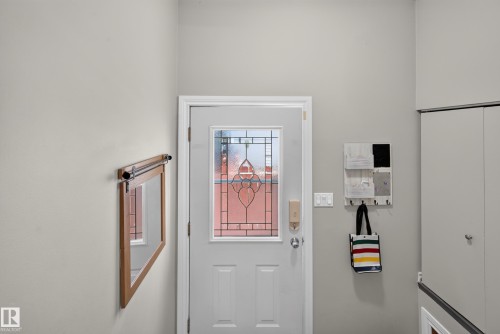 Entry door with decorative glass inserts, adjacent to built-in storage with bi-fold doors - 7704 13 Avenue Nw, Edmonton, AB 