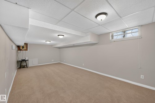 Finished lower level featuring neutral carpeting, painted walls, suspended ceiling, and recessed lighting - 7704 13 Avenue Nw, Edmonton, AB 