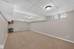 Finished lower level featuring neutral carpeting, painted walls, suspended ceiling, and recessed lighting - 