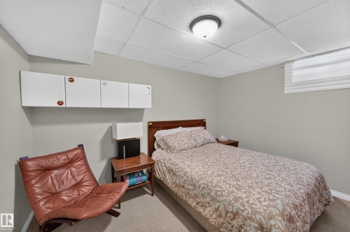 Wall-mounted cabinetry, wood-finish headboard, window with privacy blind, recessed ceiling light, and carpeted flooring - 7704 13 Avenue Nw, Edmonton, AB 
