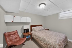 Wall-mounted cabinetry, wood-finish headboard, window with privacy blind, recessed ceiling light, and carpeted flooring - 