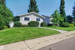 Siding exterior with white trim, mature landscaping, and an established concrete walkway - 