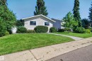 Siding exterior with white trim, mature landscaping, and an established concrete walkway - 7704 13 Avenue Nw, Edmonton, AB 