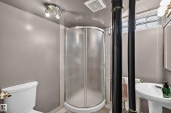 Compact three-piece bathroom featuring a corner shower, pedestal sink, and toilet - 