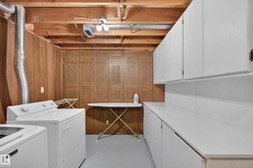 Laundry area featuring wood paneling, open ceiling joists, white cabinetry, and a white countertop - 7704 13 Avenue Nw, Edmonton, AB 