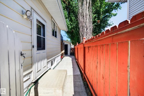 White siding exterior with an adjacent red wood fence - 7704 13 Avenue Nw, Edmonton, AB 