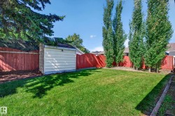 Expansive lawn area with a perimeter fence, mature trees, and an exterior storage shed - 