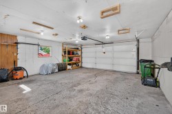 Attached garage with a roll-up door, built-in shelving, and multiple overhead light fixtures - 