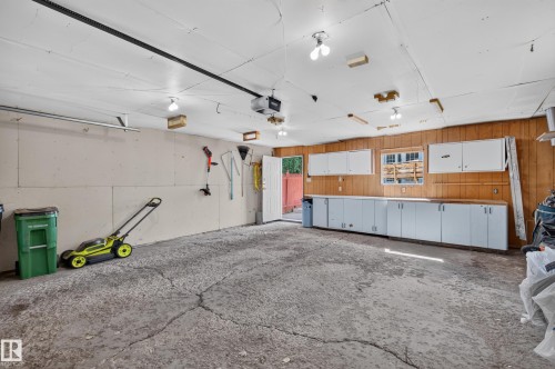 Spacious garage featuring ample built-in cabinetry, an integrated workbench, and wood paneling - 7704 13 Avenue Nw, Edmonton, AB 