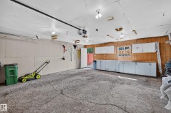 Spacious garage featuring ample built-in cabinetry, an integrated workbench, and wood paneling - 