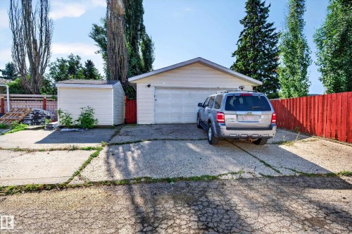 Detached garage with white siding and a white garage door, accompanied by a separate storage shed with white siding - 7704 13 Avenue Nw, Edmonton, AB 
