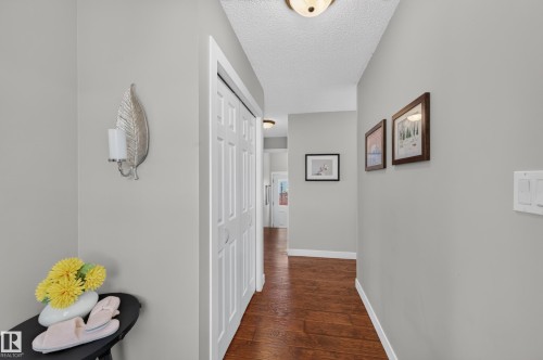 Hallway featuring wood-finish flooring, light grey walls, and a recessed ceiling light - 7704 13 Avenue Nw, Edmonton, AB 