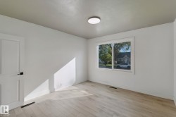 Light-colored wood-finish flooring, white walls, and a flat panel door with matte black hardware - 