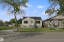 Single-family residence with light-colored siding, a dark shingled roof, a paved driveway, and a front yard with mature trees - 11914 124 Street Nw, Edmonton, AB 