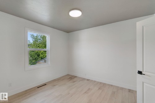Light-toned wood-finish flooring, white walls, and a window with white trim - 11914 124 Street Nw, Edmonton, AB 