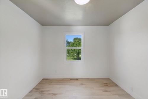 Neutral wall finishes, wood-finish flooring, and a single window with white trim - 11914 124 Street Nw, Edmonton, AB 