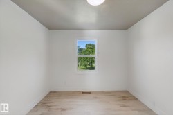 Neutral wall finishes, wood-finish flooring, and a single window with white trim - 