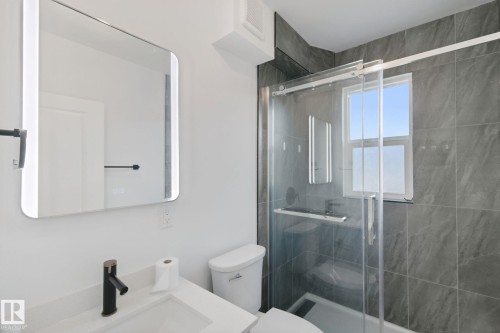 Bathroom featuring a contemporary vanity with a rectangular sink, matte black faucet, and an illuminated mirror - 11914 124 Street Nw, Edmonton, AB 