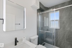Bathroom featuring a contemporary vanity with a rectangular sink, matte black faucet, and an illuminated mirror - 