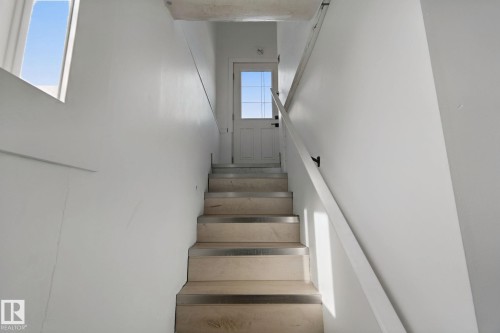 Staircase featuring light wood treads with metal accents, white walls, and a window - 11914 124 Street Nw, Edmonton, AB 