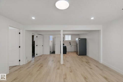 Wood-finish flooring throughout, recessed lighting, and a kitchen area with a refrigerator - 11914 124 Street Nw, Edmonton, AB 