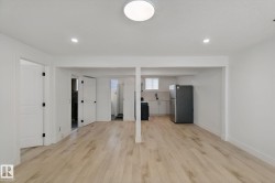 Wood-finish flooring throughout, recessed lighting, and a kitchen area with a refrigerator - 