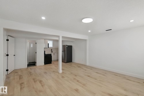 Recessed lighting, wood-finish flooring, white walls, black matte refrigerator, white cabinetry - 11914 124 Street Nw, Edmonton, AB 