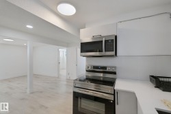 Stainless steel range and microwave, white cabinetry, solid surface countertop, and wood-finish flooring - 