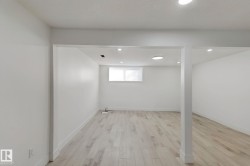 Recessed lighting, wood-finish flooring, white walls, and a window providing natural light - 