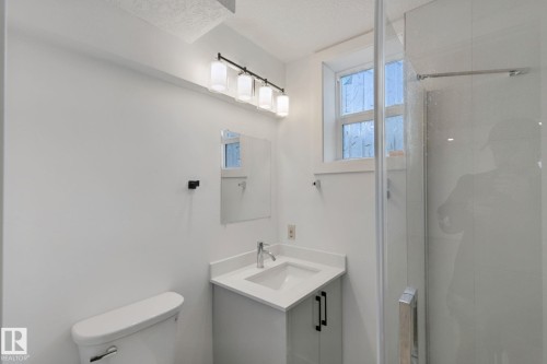 Contemporary vanity with integrated sink, sleek quartz countertop, and black hardware - 11914 124 Street Nw, Edmonton, AB 