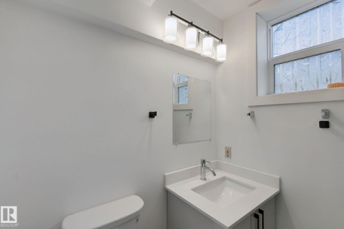 White vanity with integrated sink, chrome faucet, and a window with privacy film - 11914 124 Street Nw, Edmonton, AB 