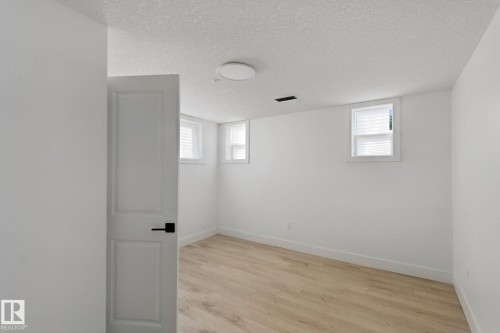 Wood-finish flooring, white walls, multiple windows, and a flush-mount ceiling light - 11914 124 Street Nw, Edmonton, AB 
