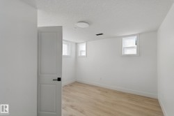 Wood-finish flooring, white walls, multiple windows, and a flush-mount ceiling light - 