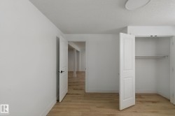 Wood-finish flooring, white walls, and a closet with bi-fold doors and integrated shelving - 
